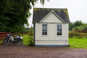 Small shed building in a back garden with bikes outside