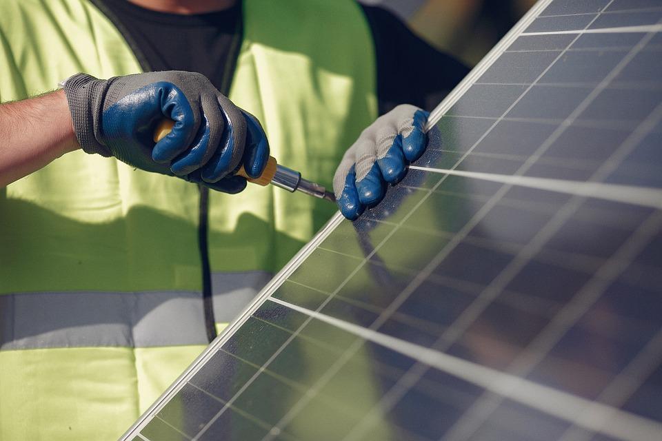 An engineer wearing high visibility fixing a solar panel